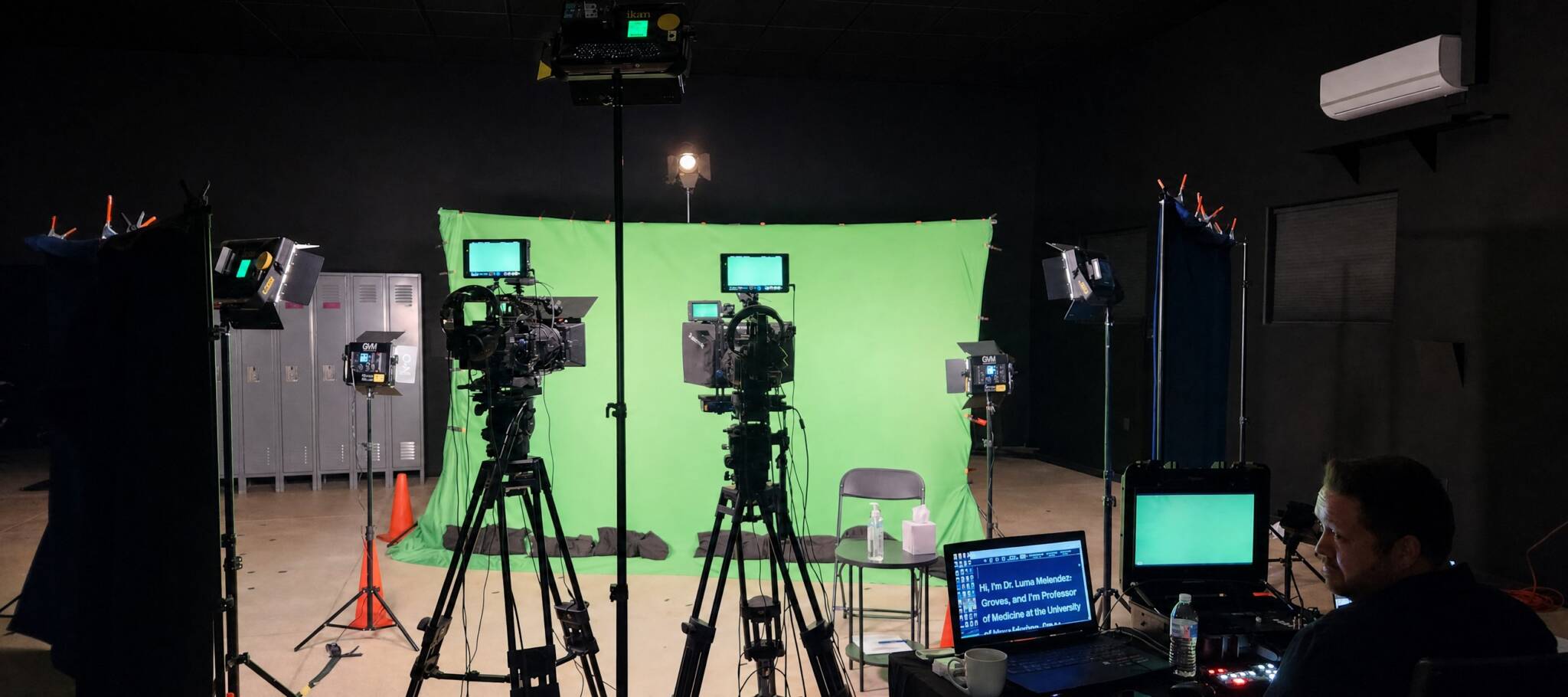 Television studio with a green chroma key backdrop and multiple cameras on tripods facing it.